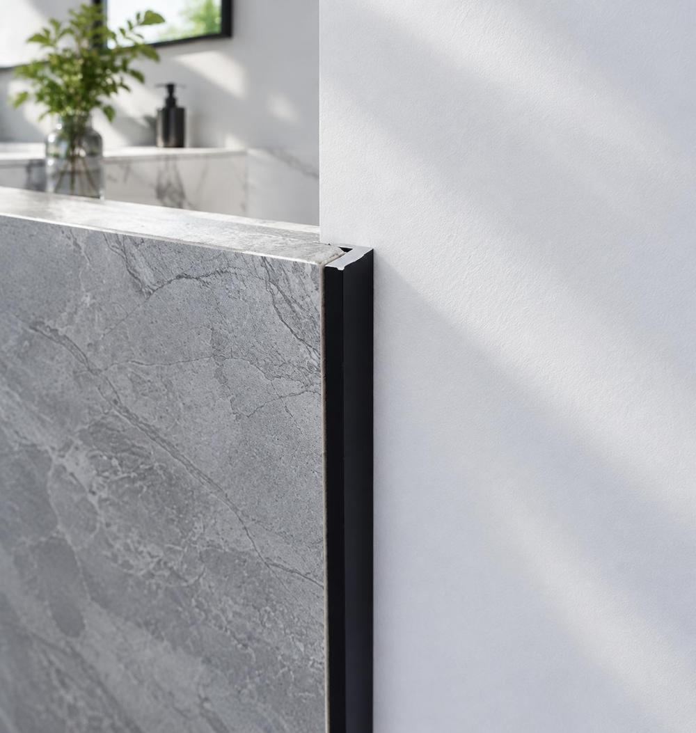Matte black aluminium angle profile edging a marble-patterned tile
