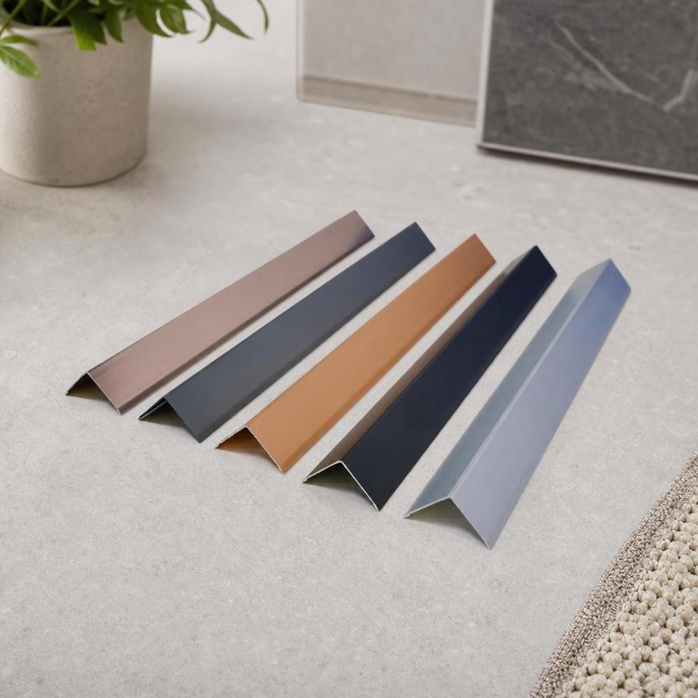 Elevated perspective showing five anodized aluminium angle profiles in various finishes including rose gold, slate grey, copper, black, and silver.